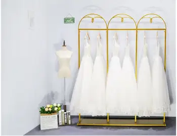 Kāzu kleitu zelta kaltas dzelzs pusē karājas plaukts apģērbu veikals pakaramais displejs stāvēt uz grīdas stāv cheongsam stāv kāzu kleita